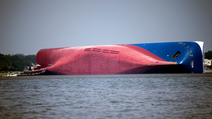 In this Sept. 9, 2019, file photo, a Moran tugboat nears the stern of the capsizing vessel Golden Ray as a tent and rescuers can be seen near the bottom of the ship near the tug boat in Jekyll Island, Ga. Marine salvage experts seeking to remove the overturned cargo ship close to Georgia's seacoast will haul it away in pieces because it cannot be safely righted and refloated intact, their Unified Command said in a statement Saturday, Oct. 12.