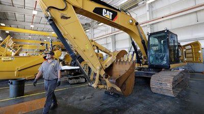 In this Sept. 18, 2019, photo, a Puckett Machinery Company technician walks past a new heavy duty Caterpillar excavator that awaits modification in Flowood, Miss.