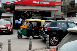 A three-wheeler drives past a Mahindra and Mahindra showroom in New Delhi, India, Oct. 1, 2019.