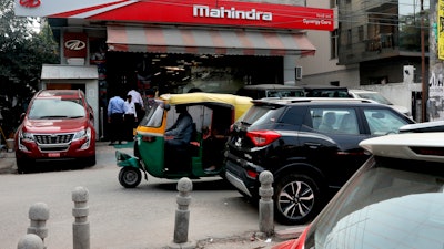 A three-wheeler drives past a Mahindra and Mahindra showroom in New Delhi, India, Oct. 1, 2019.