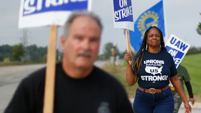 In this Monday, Sept. 30, 2019, photo, United Auto Workers members walk on the picket line during a strike at General Motors Orion Assembly plant in Orion Township, Mich.