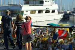 In this Sept. 6, 2019, file photo, people visit a growing memorial to the victims who died aboard the dive boat Conception as its sister boat Vision sits in the background, in Santa Barbara, Calif.
