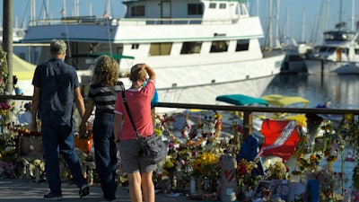 In this Sept. 6, 2019, file photo, people visit a growing memorial to the victims who died aboard the dive boat Conception as its sister boat Vision sits in the background, in Santa Barbara, Calif.