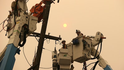 In this Nov. 9, 2018, file photo, Pacific Gas & Electric crews work to restore power lines in Paradise, Calif.