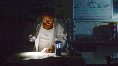 Carlos Lama of Bayside Cafe uses an LED lamp and light from his phone at the counter of the restaurant in Sausalito, Calif., Oct. 9, 2019.