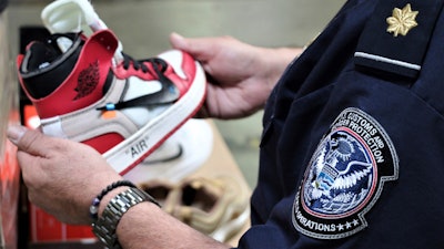 This undated photo shows an agent holding one of more than 14,800 pair of counterfeit Nike shoes, seized in a shipment arriving from China at the Los Angeles-Long Beach sports complex.