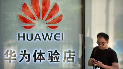 In this May 29, 2019, file photo, a man uses his smartphone outside of a shop selling Huawei products at a shopping mall in Beijing.