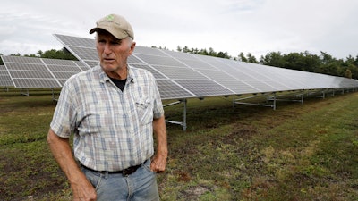 In this Oct. 2, 2019, photo, Dick Ward stands near a solar array in a cranberry bog on his farm in Carver, Mass.