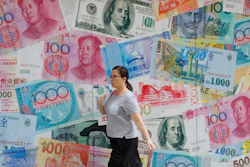 In this Aug. 6, 2019, file photo, a woman walks by a money exchange shop in Hong Kong.