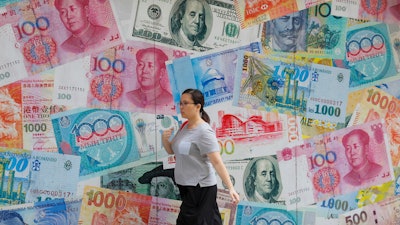 In this Aug. 6, 2019, file photo, a woman walks by a money exchange shop in Hong Kong.