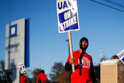 In this Oct. 9, 2019, file photo, a member of the United Auto Workers walks the picket line at the General Motors Romulus Powertrain plant in Romulus, Mich.