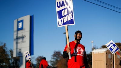 In this Oct. 9, 2019, file photo, a member of the United Auto Workers walks the picket line at the General Motors Romulus Powertrain plant in Romulus, Mich.