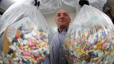 In this Sept. 11, 2019, file photo, narcotics detective Ben Hill of the Barberton Police Department shows two bags of medications stored in their headquarters.