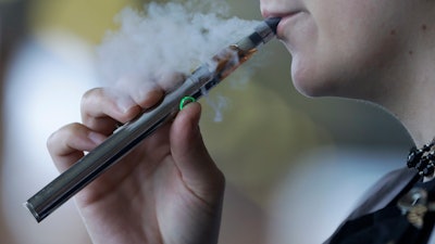 In this Friday, Oct. 4, 2019, file photo, a woman using an electronic cigarette exhales in Mayfield Heights, Ohio.