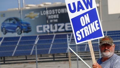 In this Sept. 16, 2019, file photo, a picketer carries sign at one of the gates outside the closed General Motors automobile assembly plant in Lordstown, Ohio.
