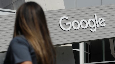 In this Sept. 24, 2019, file photo, a woman walks below a Google sign on the campus in Mountain View, Calif.