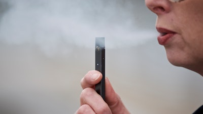 In this April 16, 2019, file photo, a woman exhales a puff of vapor from a Juul pen in Vancouver, Wash.