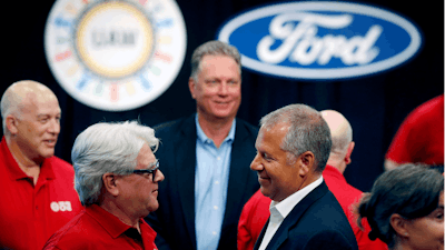 In this July 15, 2019, file photo, United Auto Workers Local 600 President Bernie Ricke, left, talks with Ford Motor Co. President-Automotive Joseph R. Hinrichs after opening contract talks in Dearborn, Mich.