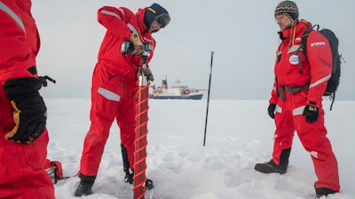 This image provided by the Alfred-Wegener-Institut shows Gunnar Spreen, left, and Matthew Shupe, right, as they exam a potential ice floe for the MOSAiC (Multidisciplinary drifting Observatory for the Study of Arctic Climate) in the Arctic Sea on Monday, Sept. 30, 2019.