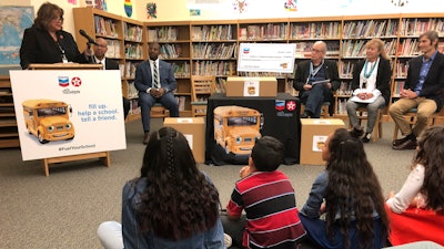 Santa Fe Public Schools Superintendent Veronica Garcia, top left, speaks about school supply donations by Chevron that are tied to local gasoline purchases at an elementary school in Santa Fe, N.M., Thursday, Oct. 3, 2019. High school students and environmental activists say that the charitable initiative promoting gasoline sales is out of step with public concerns about the state's financial dependency on the oil and natural gas sector to fund public education and government services. Chevron corporate affairs manager Tommy Lyles says the company strongly supports technology and science education.