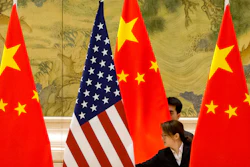 In this Feb. 14, 2019, file photo, Chinese staffers adjust U.S. and Chinese flags before the opening session of trade negotiations at the Diaoyutai State Guesthouse in Beijing.