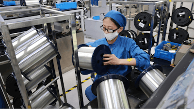 In this Aug. 14, 2019, file photo, a woman works on a production line in a fiber optics factory in Nantong in eastern China's Jiangsu province. China's factory activity shrank more sharply than expected in October amid weak consumer demand and a tariff war with Washington, a survey by an industry group showed Thursday, Oct. 31, 2019.