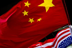 In this Nov. 7, 2012 photo, U.S. and Chinese national flags are hung outside a hotel during the U.S. Presidential election event, organized by the U.S. embassy in Beijing. Government-linked Chinese hackers have intercepted the text messages of thousands of foreigners by penetrating a telecommunications provider and planting eavesdropping software on its servers, the cybersecurity firm FireEye says.