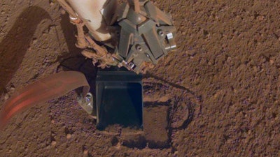 This October 2019 photo made available by NASA shows InSight's heat probe digging into the surface of Mars. On Thursday, Oct. 17, 2019, NASA says the drilling device has penetrated three-quarters of an inch (2 centimeters) over the past week, after hitting a snag seven months ago. While just a baby step, scientists are thrilled with the progress.