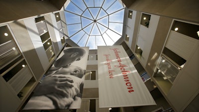 In this July 30, 2013, file photo, large banners hang in an atrium at the headquarters of Johnson & Johnson in New Brunswick, N.J. Johnson & Johnson has agreed to a $117 million multistate settlement over allegations it deceptively marketed its pelvic mesh products, which support women's sagging pelvic organs.