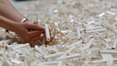 In this Friday July 26, 2019, file photo, a visitor looks through Lego pieces provided for a project at the Tate Modern, in London. Lego is testing a way for customers to ship their unwanted bricks back and get them into the hands of other kids.