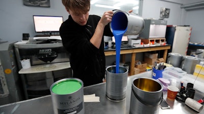 Harvey Myland prepares paint for mixing at the factory in London, Thursday, Oct. 24, 2019. Founded 135 years ago, Mylands paint factory has survived two World Wars, and now supplies film and TV productions such as 'Harry Potter'' and 'Game of Thrones,'' but Brexit is already reshaping business decisions as they increase storage and moved extra stocks to Germany.