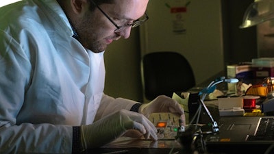 Rice University graduate student Thomas Heiderscheit demonstrates a technique to amplify the light from small concentrations of molecules on a surface by maximizing the spectral overlap between the emission and the plasmon resonance of adjacent nanoparticles. The glowing molecules can be clearly seen in the sample when excited.