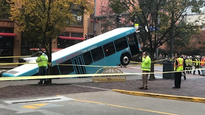 Authorities investigate after a Port Authority bus was caught in a sinkhole in downtown Pittsburgh on Monday, Oct. 28, 2019. The Port Authority of Allegheny County says the lone passenger is being treated Monday morning for minor injuries.