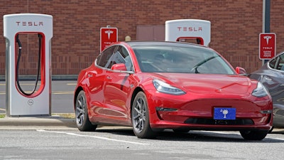 This Friday, July 19, 2019, file photo shows a Tesla vehicle charging at a Tesla Supercharger site in Charlotte, N.C. Tesla’s electric car sales accelerated again during the summer, but the company is still lagging behind the pace it needs to reach CEO Elon Musk’s goal for the entire year.