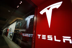 In this Feb. 9, 2019, file photo, a sign bearing the company logo is displayed outside a Tesla store in Cherry Creek Mall in Denver. The U.S. government’s highway safety agency says it’s gathering information on reports of malfunctions with a Tesla feature that lets drivers summon their cars in parking lots. The National Highway Traffic Safety Administration says it’s aware of reports about “Smart Summon” and is in contact with the company. Messages were left Thursday seeking comment from Tesla.