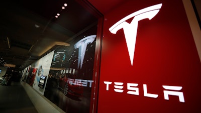 In this Feb. 9, 2019, file photo, a sign bearing the company logo is displayed outside a Tesla store in Cherry Creek Mall in Denver. The U.S. government’s highway safety agency says it’s gathering information on reports of malfunctions with a Tesla feature that lets drivers summon their cars in parking lots. The National Highway Traffic Safety Administration says it’s aware of reports about “Smart Summon” and is in contact with the company. Messages were left Thursday seeking comment from Tesla.