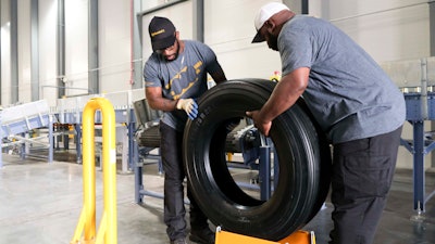 Travis Chambliss, left, and Jason Wallace unload the first tire produced at the Clinton Continental Tire Plant from a conveyor belt during the Continental Tire Grand Opening in Clinton, Miss., Wednesday, Oct. 16, 2019.