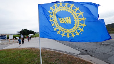 In this Sept. 30, 2019, file photo a UAW flag flies near strikers outside the General Motors Orion Assembly plant in Orion Township, Mich. A General Motors contract offer to striking union members has wage increases or lump-sum payments in all four years. But a person briefed on the offer says it was rejected because it took money from other places to fund profit sharing and didn’t give temporary workers a clear path to a full-time job. Still, the offer made late Monday is likely to be the framework for whatever agreement is reached to end the strike by 49,000 workers that has halted production in the U.S. and severely cut output in Mexico and Canada.
