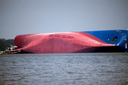In this Sept. 9, 2019, file photo, a Moran tugboat nears the stern of the capsizing vessel Golden Ray as a tent and rescuers can be seen near the bottom of the ship near the tug boat in Jekyll Island, Ga. Marine salvage experts seeking to remove the overturned cargo ship close to Georgia's seacoast will haul it away in pieces because it cannot be safely righted and refloated intact, their Unified Command said in a statement Saturday, Oct. 12.