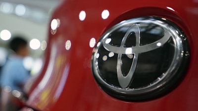 In this Aug. 2, 2019, file, photo, people walk by the logo of Toyota at a show room in Tokyo.