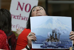 In this Feb. 10, 2016, file photo, Francesca Siena holds a photo of Mount Rainier and the Port of Tacoma that has been computer modified to include the image of a refinery.
