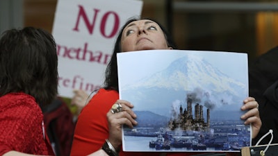 In this Feb. 10, 2016, file photo, Francesca Siena holds a photo of Mount Rainier and the Port of Tacoma that has been computer modified to include the image of a refinery.