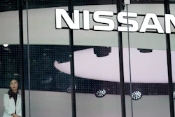 In this July 25, 2019, photo, a staff member stands by a window of a Nissan car gallery in Tokyo.