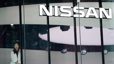 In this July 25, 2019, photo, a staff member stands by a window of a Nissan car gallery in Tokyo.