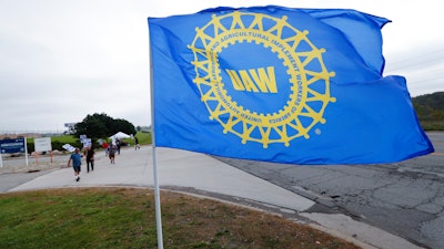 In this Sept. 30, 2019, file photo, a UAW flag flies near strikers outside the General Motors Orion Assembly plant in Orion Township, Mich.