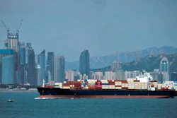 In this Sept. 13, 2018, file photo, a container ship sails by the business district in Qingdao, China.