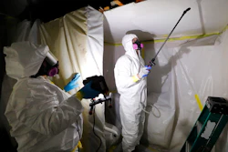 In this Oct. 18, 2017, file photo, Asbestos Removal Technologies Inc. job superintendent Ryan Laitila, right, sprays amended water as job foreman Megan Eberhart holds a light during asbestos abatement in Howell, Mich.