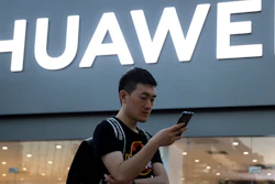 In this May 20, 2019, file photo, a man uses his smartphone outside a Huawei store in Beijing.