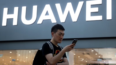 In this May 20, 2019, file photo, a man uses his smartphone outside a Huawei store in Beijing.