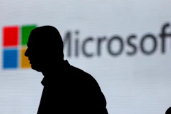 In this Nov. 7, 2017, file photo, an unidentified man is silhouetted as he walks in front of Microsoft logo at an event in New Delhi, India.